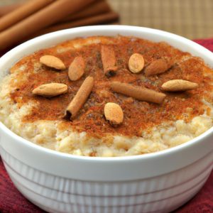 A white bowl filled with creamy Indian rice pudding and topped with cinnamon and sliced almonds.