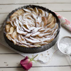 A 9-inch tart pan filled with a stunning rose-shaped tart made with thinly sliced apples, with a golden-brown crust and a light dusting of powdered sugar on top.