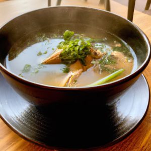 A beautiful bowl of steaming Japanese Chicken Soup with a garnish of fresh herbs