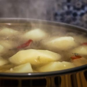 Close up of bubbling pot of Mediterranean Potato Soup with steam rising from it.