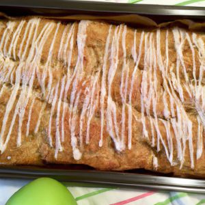 A golden-brown loaf of French Apple Fritter Bread on a baking sheet with apple slices and cinnamon sugar sprinkled on top.
