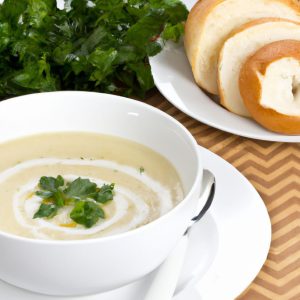 A bowl of creamy potato soup garnished with parsley and served with a side of crusty bread.