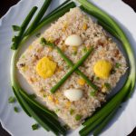 A plate of egg fried rice with vegetables arranged in a yin-yang pattern, with a few pieces of green onion on top.