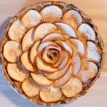 An overhead view of a cooked, golden brown, Mediterranean Apple Rose Tart. The tart is decorated with overlapping apple slices that form a rose pattern.