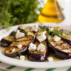 A plate of grilled eggplant with feta and olives on a white plate with fresh herbs and olive oil in the background.