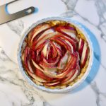 A picture of a freshly-baked Chinese-inspired Apple Rose Tart in a tart pan on a white marble countertop.