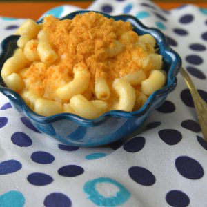 A bowl of creamy, cheesy mac and cheese with a dollop of butter and sprinkling of bread crumbs.