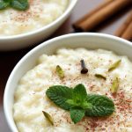 A bowl of creamy, comforting Indian rice pudding topped with ground cardamom and fresh mint leaves.