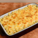 A 9x13 baking dish filled with creamy macaroni and cheese topped with lightly browned cheese.
