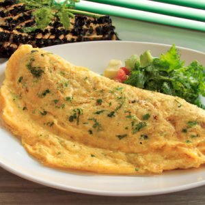 A golden, fluffy omelet filled with fresh vegetables, herbs, and cheese, on a white plate with a wooden cutting board in the background.