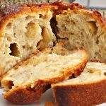 A round loaf of freshly-baked slow cooker French apple fritter bread, cut in half and revealing its soft, fluffy interior.