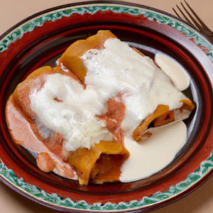 A plate of freshly made Mexican-style pressure cooked chicken enchiladas with melted cheese and a dollop of sour cream.