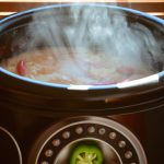 A close up of a slow cooker with a Mexican breakfast inside, steam rising from the slow cooker.
