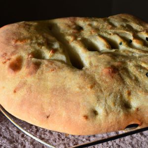 A loaf of Italian Focaccia Bread fresh from the oven, with a golden-brown crust and a soft interior.