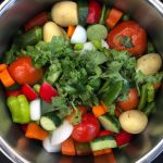 A large pot filled with colorful vegetables and herbs, ready to be cooked.
