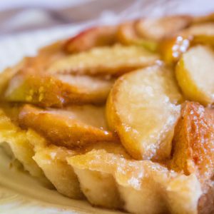 A golden brown French apple tart with a flaky, buttery crust, sprinkled with sugar and cinnamon.