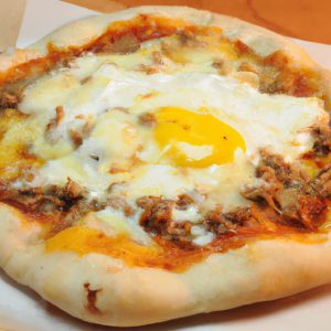 A golden brown Italian breakfast pizza with melted cheese and eggs, perched on top of a freshly-baked crust.