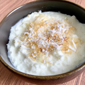 A bowl of creamy, sweet Indian Coconut Rice Pudding with a dollop of cream and a sprinkle of toasted coconut flakes
