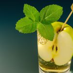 A refreshing and healthy French Apple-Mint Spritzer in a highball glass with a sprig of mint and a thin slice of green apple.