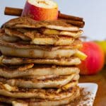 A stack of delicious apple pie pancakes topped with sliced apples and a sprinkle of cinnamon