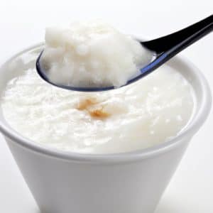 A bowl of creamy Chinese coconut rice pudding with a spoon sticking out of it.